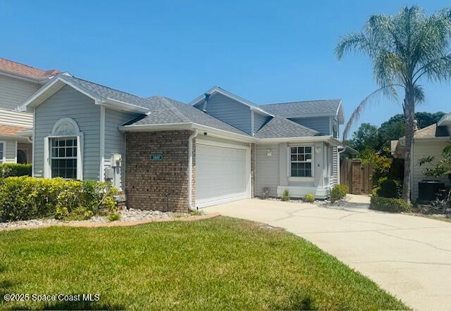 view of front of home with an attached garage, a front yard, concrete driveway, and brick siding