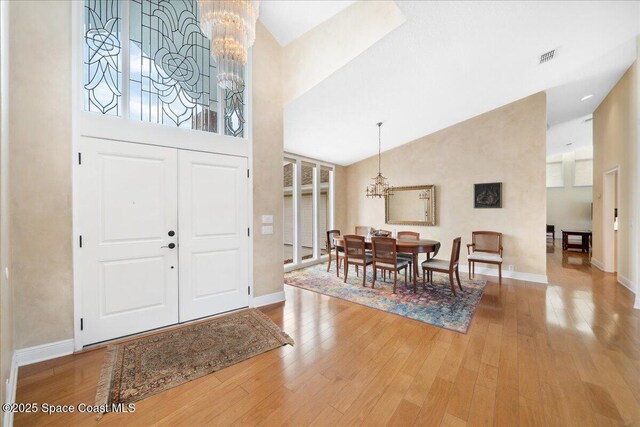 649 Spring Lake Dr, Melbourne, FL 32940 - entryway with a chandelier, high vaulted ceiling, wood finished floors, and baseboards