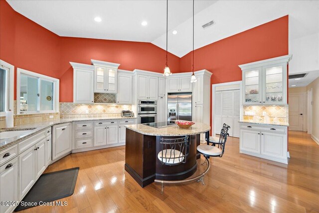 649 Spring Lake Dr, Melbourne, FL 32940 - kitchen with appliances with stainless steel finishes, decorative backsplash, white cabinetry, a sink, and high vaulted ceiling
