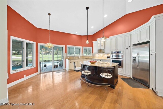 649 Spring Lake Dr, Melbourne, FL 32940 - kitchen with appliances with stainless steel finishes, high vaulted ceiling, backsplash, white cabinets, and pendant lighting