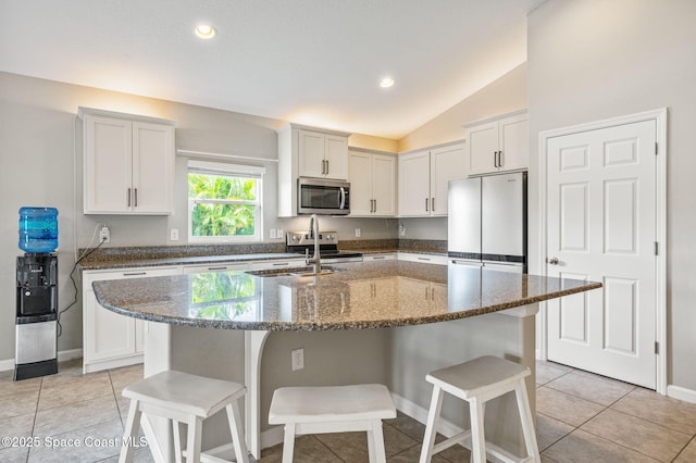 4065 Harvest Cir, Rockledge, FL 32955 - kitchen featuring appliances with stainless steel finishes, a sink, a breakfast bar area, lofted ceiling, and dark stone counters