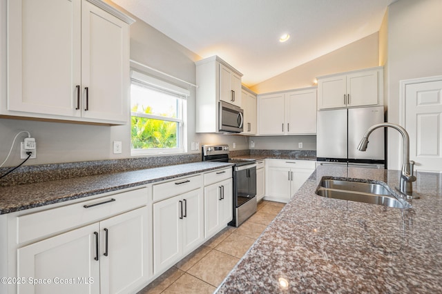 4065 Harvest Cir, Rockledge, FL 32955 - kitchen featuring appliances with stainless steel finishes, a sink, vaulted ceiling, light tile patterned flooring, and dark stone countertops