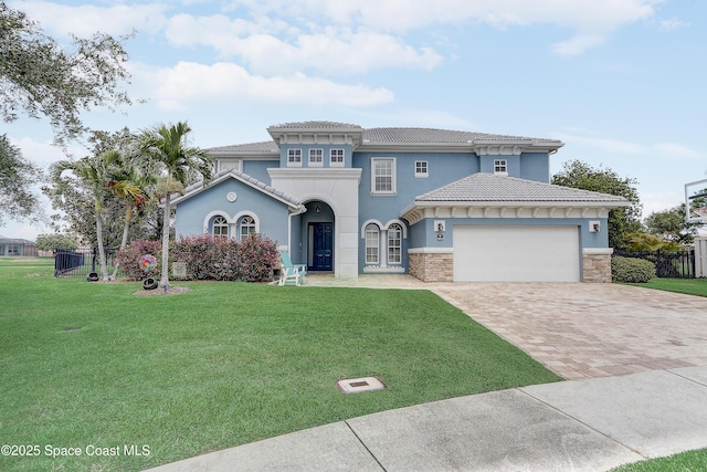 mediterranean / spanish home featuring an attached garage, decorative driveway, stucco siding, a tile roof, and stone siding