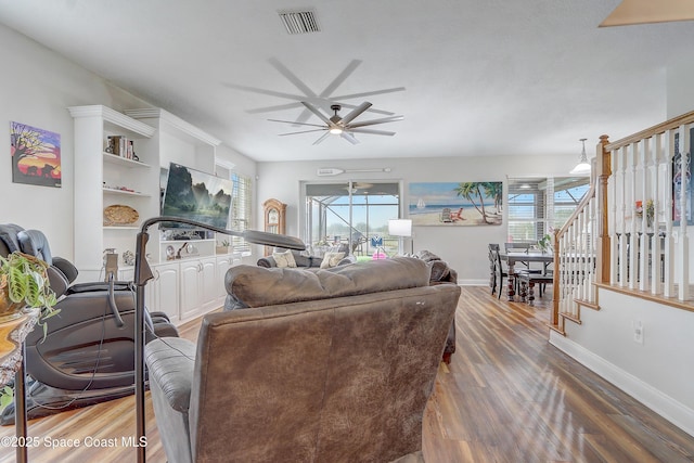 living room with a ceiling fan, wood finished floors, plenty of natural light, and baseboards