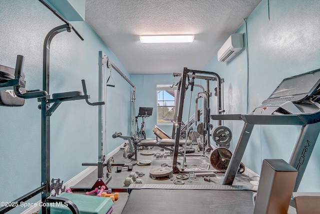 exercise area with a wall mounted AC, a textured ceiling, and baseboards