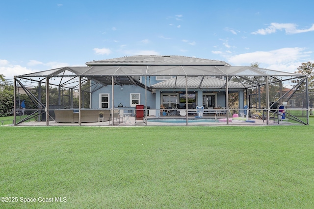 back of property with a patio, a lawn, and a lanai