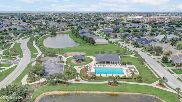 aerial view of property and surrounding area with a nearby body of water, a pool, and nearby suburban area