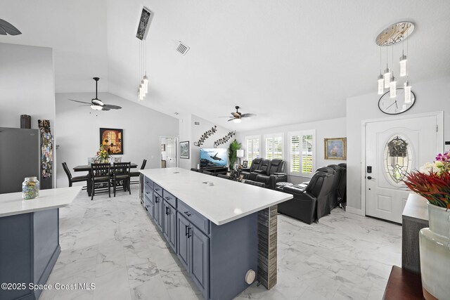kitchen featuring ceiling fan, light marble finish flooring, light countertops, lofted ceiling, and pendant lighting