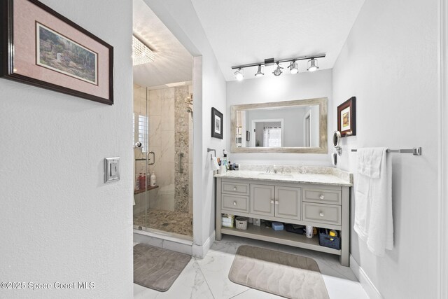 bathroom featuring a stall shower, vanity, marble finish floors, baseboards, and track lighting
