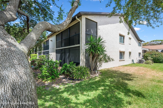 5807 N Atlantic Ave Unit 521, Cape Canaveral, FL 32920 - view of home's exterior with central AC unit, stucco siding, and a lawn