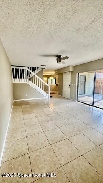 1648 S Park Ave, Titusville, FL 32780 - tiled empty room featuring a ceiling fan, baseboards, a textured ceiling, and stairs
