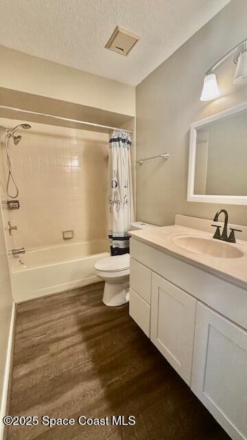1648 S Park Ave, Titusville, FL 32780 - bathroom featuring toilet, shower / bathtub combination with curtain, wood finished floors, vanity, and a textured ceiling