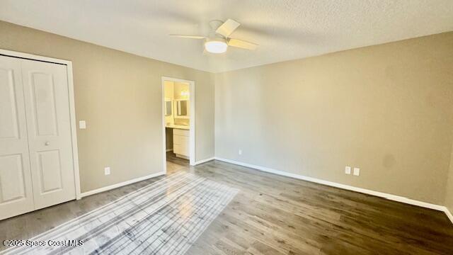 1648 S Park Ave, Titusville, FL 32780 - unfurnished bedroom with wood finished floors, baseboards, ceiling fan, ensuite bathroom, and a closet