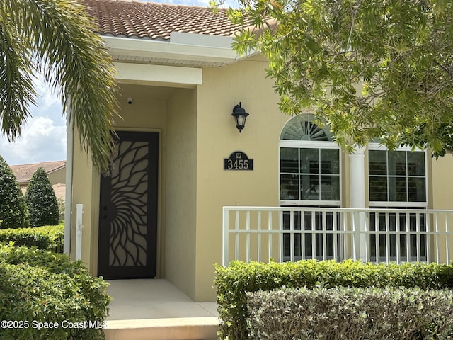 doorway to property featuring stucco siding and a tiled roof