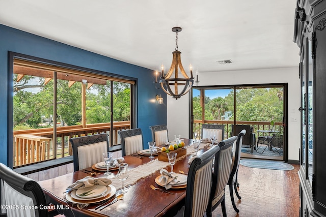 dining space featuring a chandelier, plenty of natural light, and wood finished floors