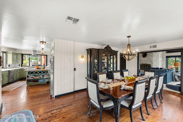 dining area with a chandelier, dark wood-style flooring, plenty of natural light, and baseboards