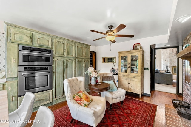 kitchen with green cabinets, double oven, ceiling fan, and dark wood-style floors
