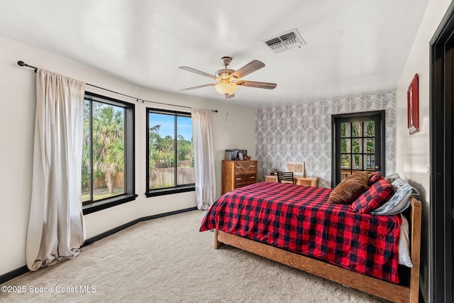 carpeted bedroom featuring wallpapered walls, baseboards, an accent wall, and a ceiling fan