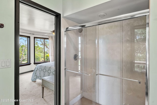 ensuite bathroom featuring a ceiling fan and a stall shower
