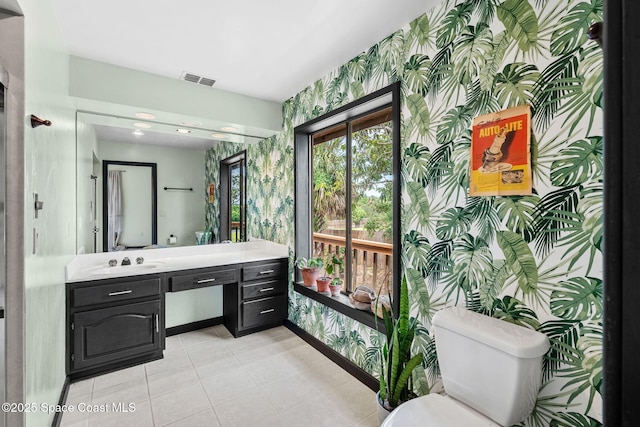bathroom with wallpapered walls, toilet, vanity, baseboards, and tile patterned floors