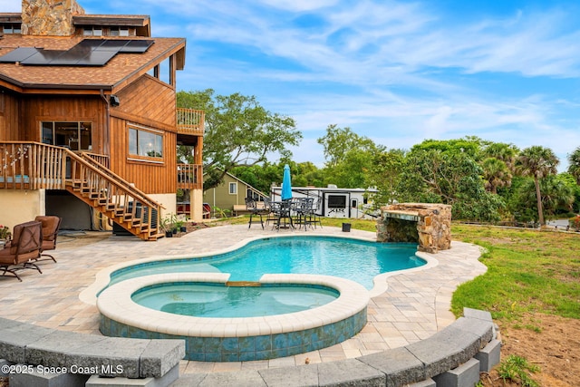view of pool featuring a pool with connected hot tub, a patio area, and stairs