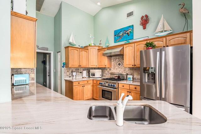 1132 Cypress Trace Dr, Melbourne, FL 32940 - kitchen featuring appliances with stainless steel finishes, wall chimney range hood, high vaulted ceiling, backsplash, and light stone countertops