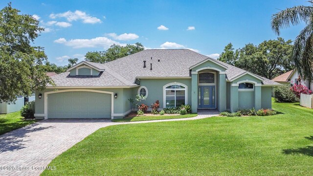 1132 Cypress Trace Dr, Melbourne, FL 32940 - view of front facade featuring stucco siding, a garage, a front yard, driveway, and a shingled roof