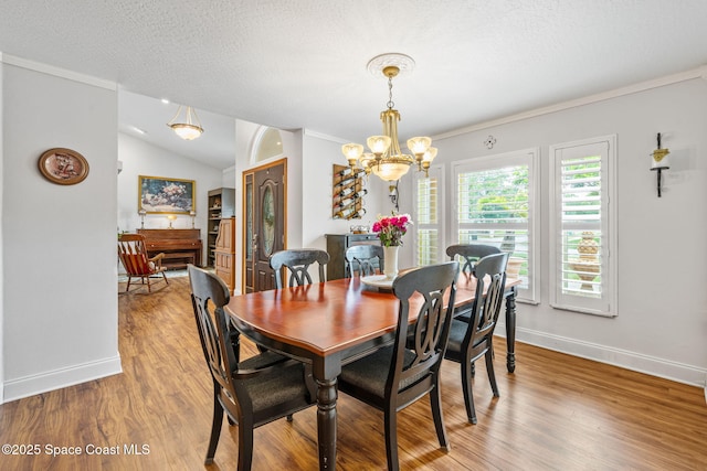 2449 Willowbrook Rd, Merritt Island, FL 32952 - dining area featuring a chandelier, light wood-type flooring, baseboards, ornamental molding, and vaulted ceiling