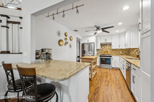 2449 Willowbrook Rd, Merritt Island, FL 32952 - kitchen with appliances with stainless steel finishes, a sink, ceiling fan, tasteful backsplash, and a kitchen bar