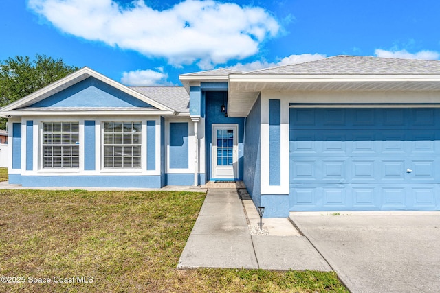 view of front of property with an attached garage, a front yard, and stucco siding