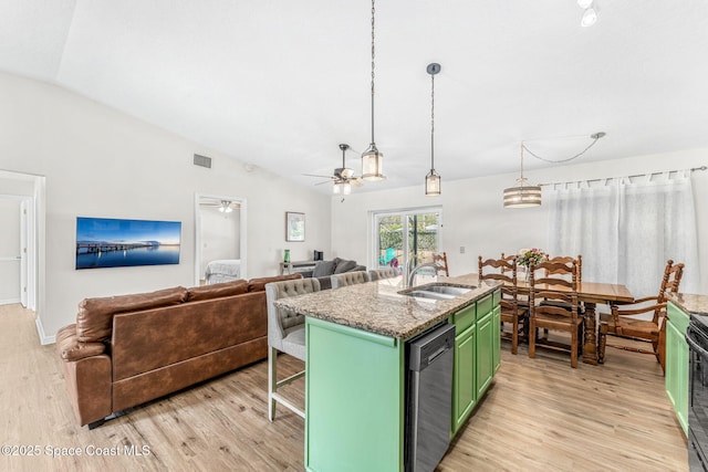 kitchen with green cabinetry, stainless steel dishwasher, a sink, light wood-style flooring, and vaulted ceiling