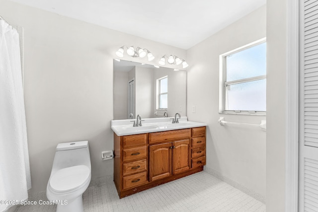 bathroom featuring toilet, double vanity, and baseboards