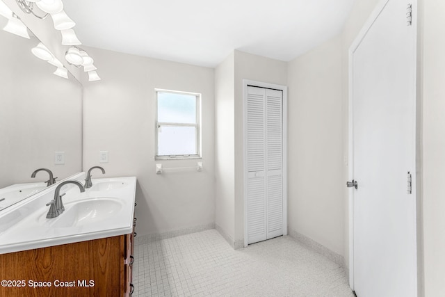 bathroom featuring a closet, double vanity, and baseboards