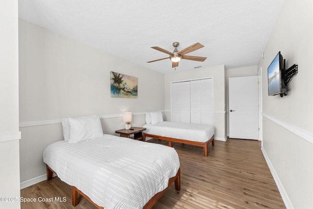 bedroom with wood finished floors, a closet, baseboards, and ceiling fan