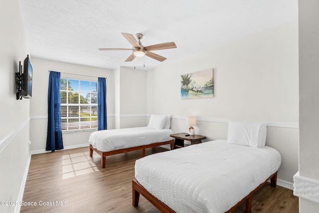 bedroom with wood finished floors, baseboards, and a ceiling fan