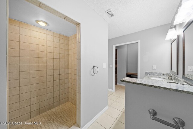 255 S Tropical Trl Unit B3, Merritt Island, FL 32952 - bathroom with tile patterned flooring, vanity, tiled shower, a textured ceiling, and baseboards