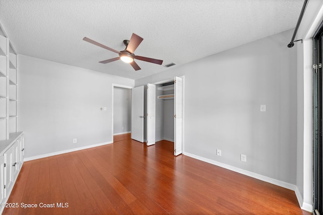 255 S Tropical Trl Unit B3, Merritt Island, FL 32952 - unfurnished bedroom with wood finished floors, a textured ceiling, a closet, baseboards, and ceiling fan