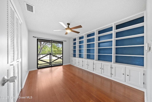 255 S Tropical Trl Unit B3, Merritt Island, FL 32952 - spare room featuring a textured ceiling, ceiling fan, baseboards, built in shelves, and wood finished floors