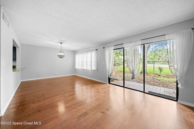 255 S Tropical Trl Unit B3, Merritt Island, FL 32952 - empty room featuring wood finished floors, a chandelier, a textured ceiling, and baseboards