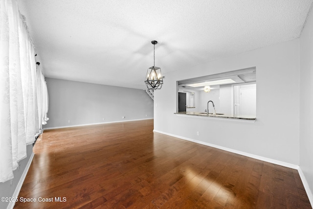 255 S Tropical Trl Unit B3, Merritt Island, FL 32952 - unfurnished living room featuring a sink, wood finished floors, baseboards, a chandelier, and a textured ceiling