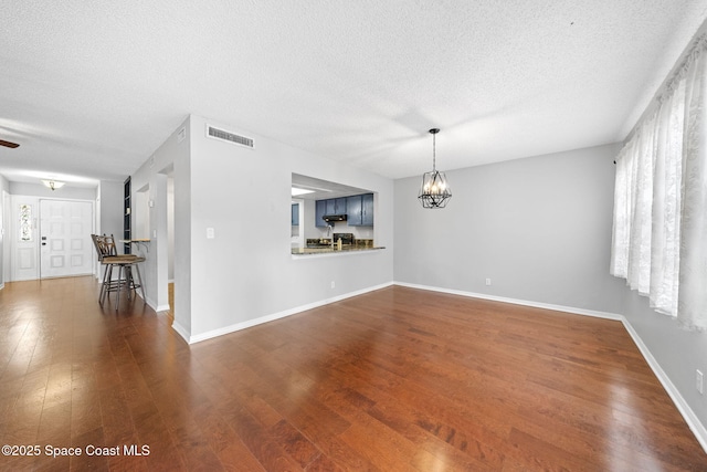 255 S Tropical Trl Unit B3, Merritt Island, FL 32952 - unfurnished living room featuring a chandelier, wood finished floors, a textured ceiling, and baseboards