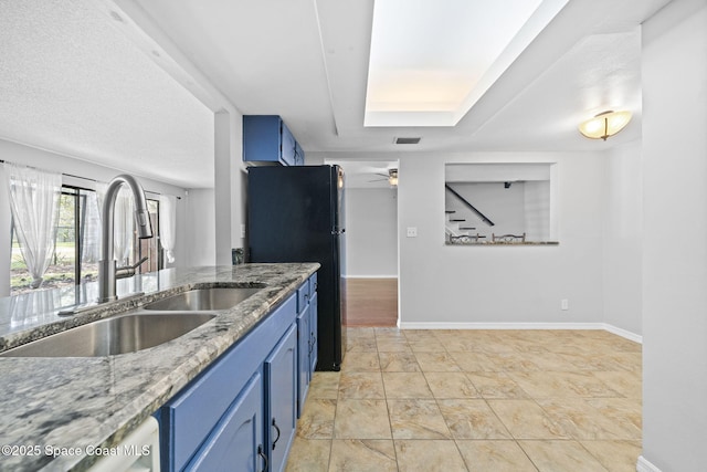 255 S Tropical Trl Unit B3, Merritt Island, FL 32952 - kitchen featuring a sink, blue cabinetry, freestanding refrigerator, baseboards, and light stone countertops