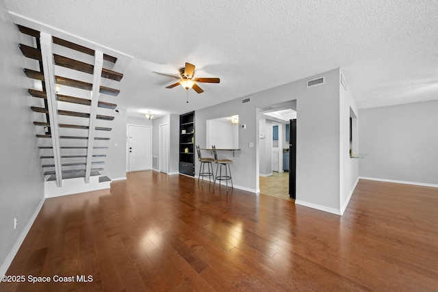 255 S Tropical Trl Unit B3, Merritt Island, FL 32952 - unfurnished living room featuring ceiling fan, a textured ceiling, baseboards, wood finished floors, and built in features