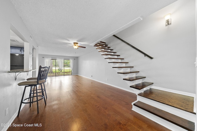 255 S Tropical Trl Unit B3, Merritt Island, FL 32952 - unfurnished living room with a ceiling fan, stairs, a textured ceiling, wood finished floors, and baseboards