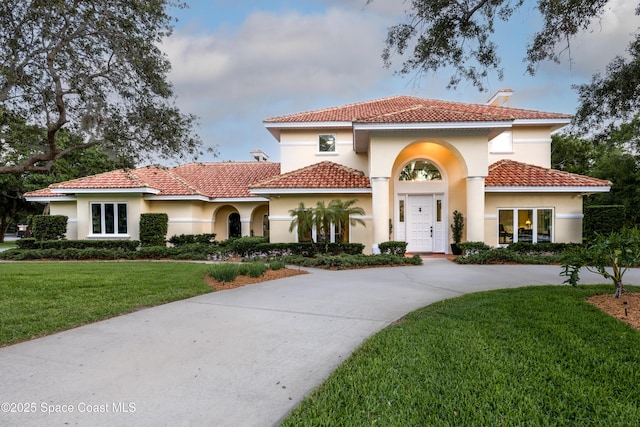 175 Stewart Dr, Merritt Island, FL 32952 - mediterranean / spanish-style home featuring stucco siding, a front yard, curved driveway, and a tile roof