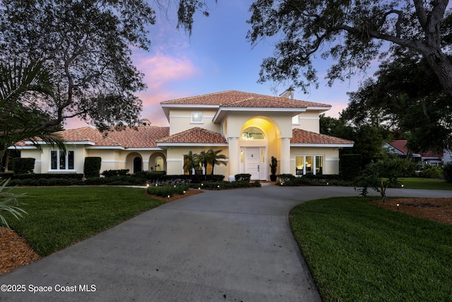 175 Stewart Dr, Merritt Island, FL 32952 - mediterranean / spanish-style home with stucco siding, a front lawn, curved driveway, a chimney, and a tile roof