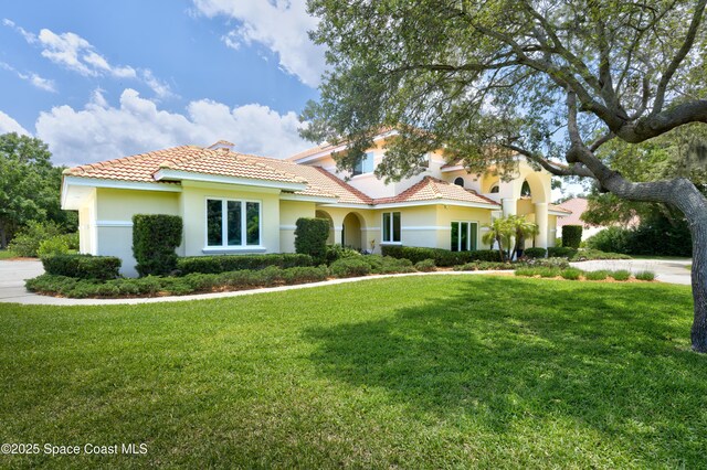 175 Stewart Dr, Merritt Island, FL 32952 - mediterranean / spanish-style home featuring a tile roof, a front yard, and stucco siding