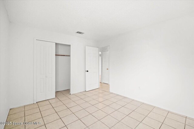 326 Brescia St NE, Palm Bay, FL 32907 - unfurnished bedroom with a closet, a textured ceiling, and light tile patterned flooring