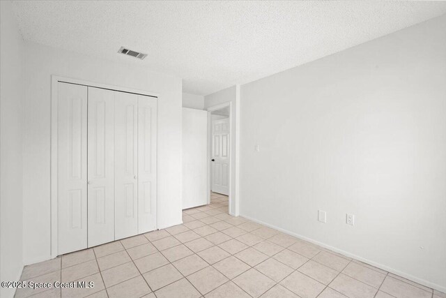 326 Brescia St NE, Palm Bay, FL 32907 - unfurnished bedroom featuring a textured ceiling, a closet, light tile patterned floors, and baseboards
