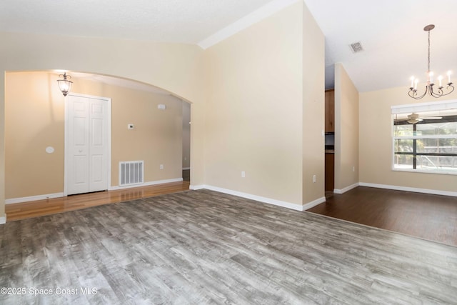 5230 Everett St, Cocoa, FL 32927 - empty room featuring vaulted ceiling, a chandelier, arched walkways, wood finished floors, and baseboards